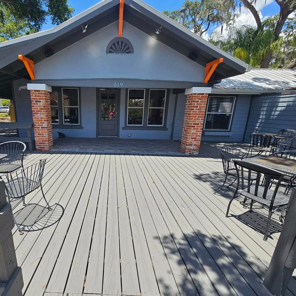 Exterior of United Smokehouse with a gray building, orange accents, and an outdoor dining deck.