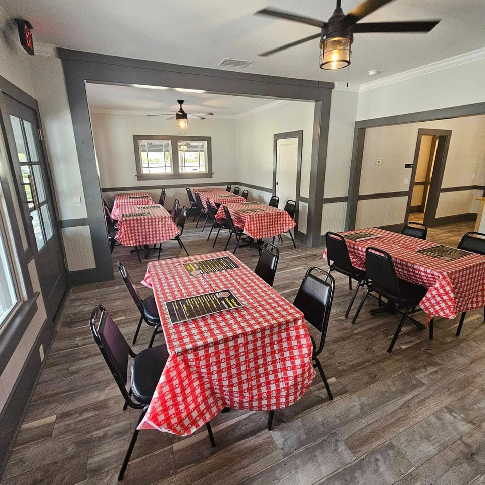 Dining room at United Smokehouse with multiple tables covered in red and white checkered tablecloths.